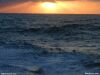 Photo of sun setting over waves in the sea, troubled water