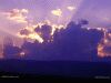 Photo of sun rays shining from behind dark clouds at sunset