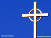 white steeple cross against a bright blue sky, not centered