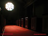 Darkened church aisle with red carpet pointing toward a backlight round window