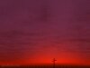 photo of a cross silhouetted against a deep red sunset