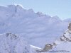 Full screen photo of snow covered mountain against a light sky, low contrast