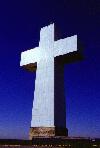 Color photo of Illinois cross against blue sky, centered, vertical.
