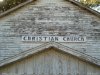 Color photo of old church, says 'christisn church' on sign, time passing, aging.