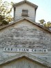 Vertical color photo of old Christian Church with faded paint, falling apart.