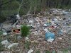 color photo of 'no dumping' sign in a field of trash, pollution, laws