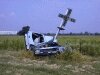 color photo of car wrecked against train crossing post, uncertainty