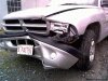Color photo of wrecked car fender with a faith license plate